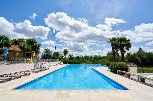 une grande piscine avec chaises et palmiers dans l'établissement Glamping Dordogne, à Douville
