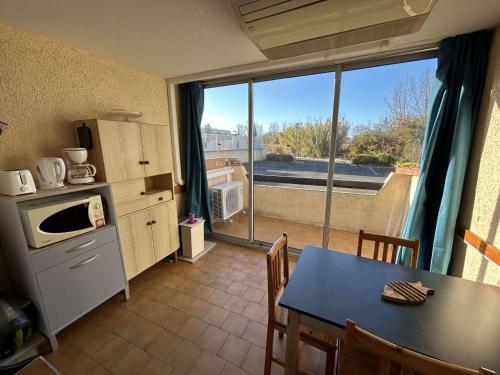 une cuisine avec une table et une grande fenêtre dans l'établissement Appartement lumineux, piscine, proche plage et commerces - FR-1-387-168, à Marseillan