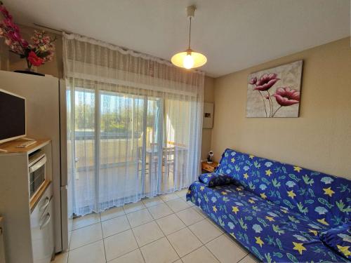 un salon avec un canapé bleu et une fenêtre dans l'établissement Appartement lumineux, piscine, proche plage et commerces - FR-1-387-168, à Marseillan