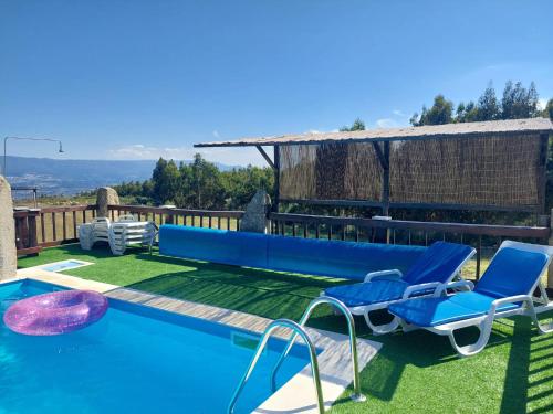 a swimming pool with two blue chairs next to a house at Quinta Do Marmeiral in Mangualde