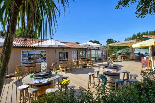 un patio extérieur avec tables, chaises et parasols dans l'établissement Glamping Vendée, à Saint-Julien-des-Landes