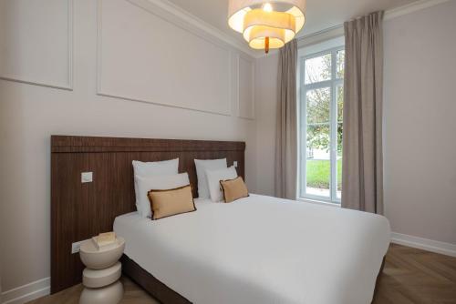 a bedroom with a large white bed and a window at L'Horloge - Appart'Hotel proche de Disneyland in Montévrain