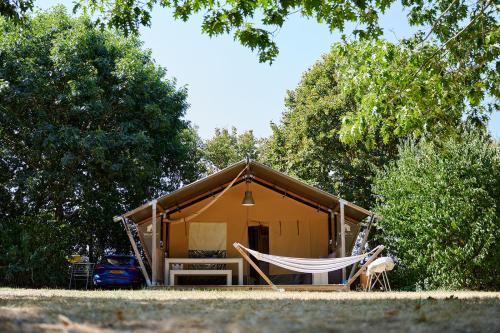 a tent with a hammock in front of it at Glamping Vendée in Saint-Julien-des-Landes