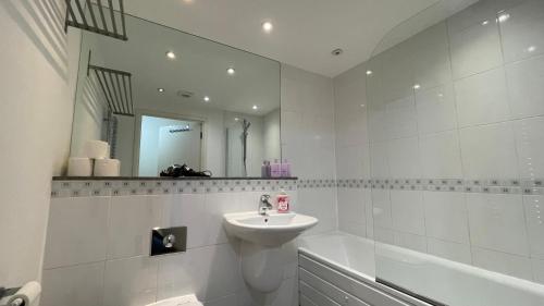 a white bathroom with a sink and a bath tub at Stratford 2 bedroom Apartment with 2 Bathrooms & Great Links in London