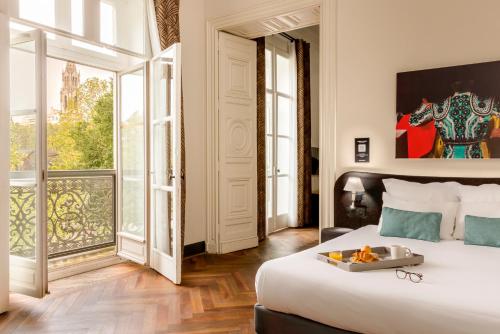 a bedroom with a large bed and a large window at Appart'City Collection Nîmes Arènes in Nîmes