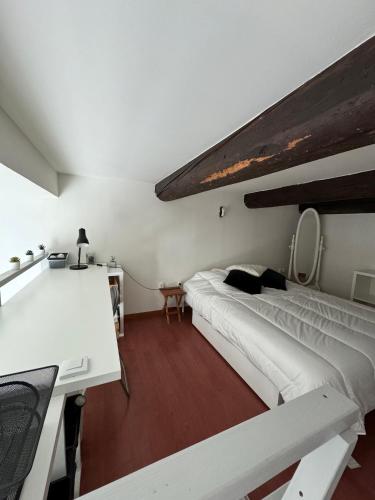 un grand lit blanc dans une chambre avec un bureau dans l'établissement Au pied des Halles - 46m2 en centre ville - 1 chambre et 1 mezzanine - tout confort, à Sète