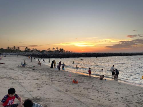 un groupe de personnes sur la plage au coucher du soleil dans l'établissement Cozy zone, à Charjah