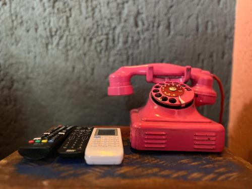a red phone sitting next to two remote controls at Chalés Calima in Lençóis