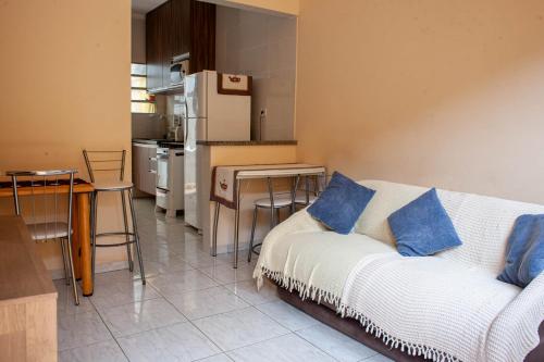 a living room with a white couch and a kitchen at Casa aconchegante c churrasqueira a 400m da praia in Samaritá