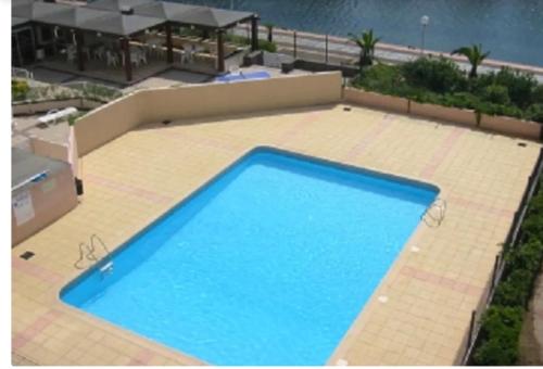 une grande piscine bleue sur un patio carrelé dans l'établissement Coquet T3 bord lagon bras de mer cap d'Agde, au Cap d'Agde
