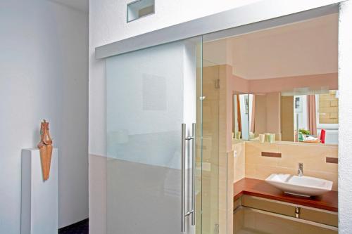 a glass shower door in a bathroom with a sink at Keramikhotel Goldener Brunnen in Gmunden