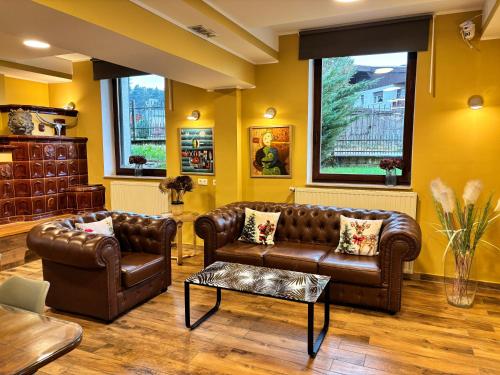 a living room with brown leather furniture and yellow walls at Hotel Pohorje in Maribor