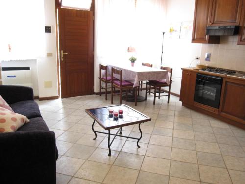 a kitchen and living room with a table and a couch at Appartamento Pineta in Grado