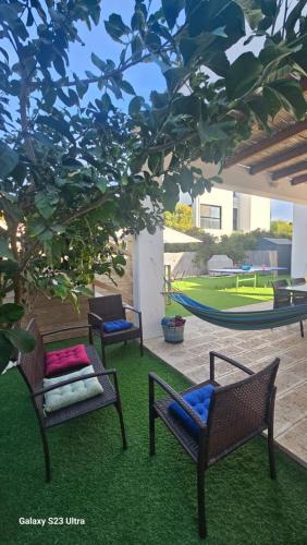 three chairs and a hammock in a yard at הבית בחוף הזהב in Caesarea