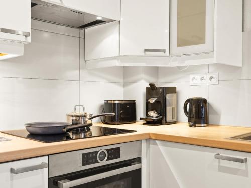 une cuisine avec des armoires blanches et un four à plaques de cuisson dans l'établissement Apartment Fer à Cheval-1 by Interhome, à Châtel