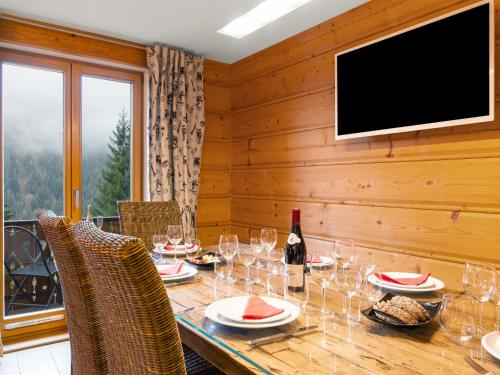 une salle à manger avec une table, des verres à vin et une télévision dans l'établissement Apartment Fer à Cheval-3 by Interhome, à Châtel