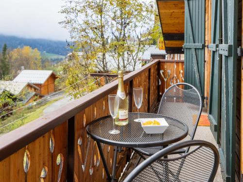 une table et des chaises sur un balcon avec une bouteille et des verres dans l'établissement Apartment Fer à Cheval-3 by Interhome, à Châtel