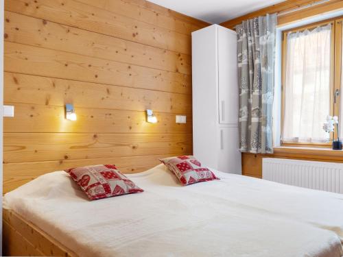 een slaapkamer met houten wanden en een bed met 2 kussens bij Apartment Fer à Cheval-2 by Interhome in Châtel