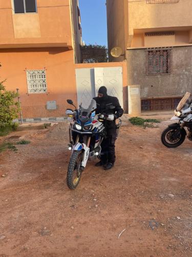 a man sitting on a motorcycle in front of a building at Spacious Apartment with Motorcycle Garage, Free Parking, and Air Conditioning in Er Rachidia