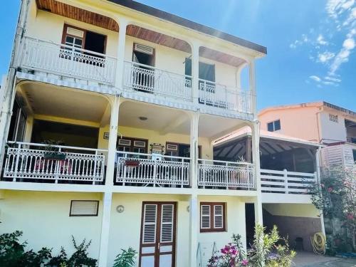 a white building with white balconies and white railings at Maison charmante avec vue sur la mer et montagnes, Les Anses-d'Arlet. in Les Anses-dʼArlets