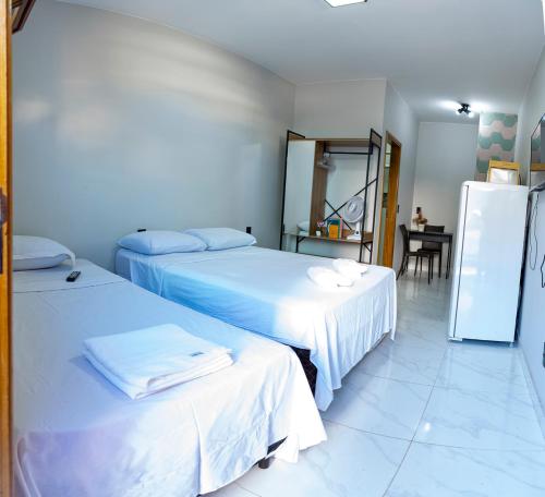 a room with two beds and a refrigerator at Studio equipado na area central com Wi-Fi in Alfenas