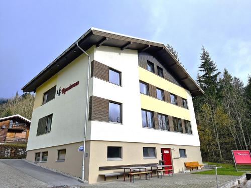 a white building with a red door and picnic tables at Holiday Home Runnimoos-1 by Interhome in Innerlaterns
