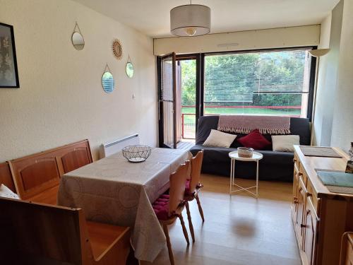 a living room with a table and a couch at Studio cosy avec terrasse au cœur du village in Xonrupt-Longemer