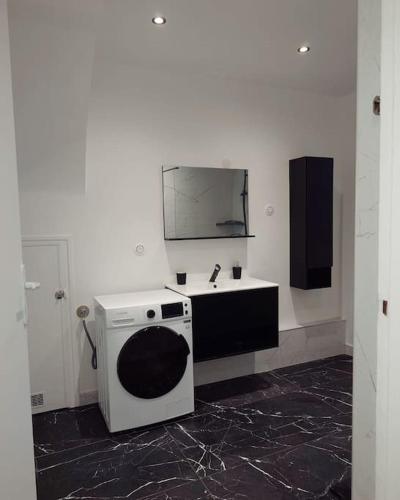 une salle de bain avec un lavabo et un miroir au mur dans l'établissement Cosy Appartement proche Paris, à Villeparisis
