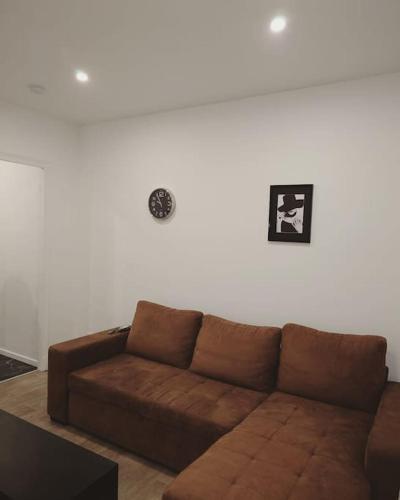 - un salon avec un canapé marron et un mur blanc dans l'établissement Cosy Appartement proche Paris, à Villeparisis