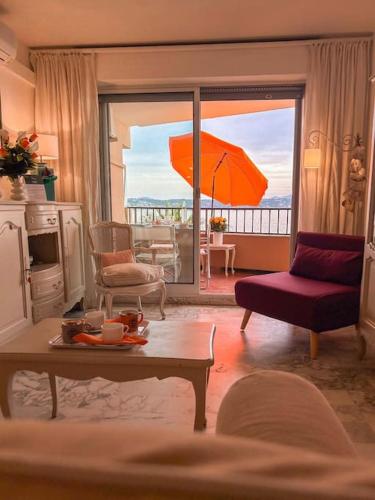 - un salon avec une table et un parasol orange dans l'établissement T3 Bandol vue mer - Les pieds dans l'eau, à Bandol