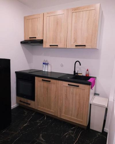 - une cuisine avec un évier noir et des placards en bois dans l'établissement Cosy Appartement proche Paris, à Villeparisis