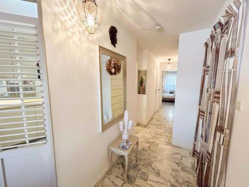 un couloir avec des murs blancs, une table et un miroir dans l'établissement T3 Bandol vue mer - Les pieds dans l'eau, à Bandol