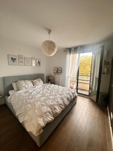 une chambre avec un grand lit et une grande fenêtre dans l'établissement Le Central, à Colombes