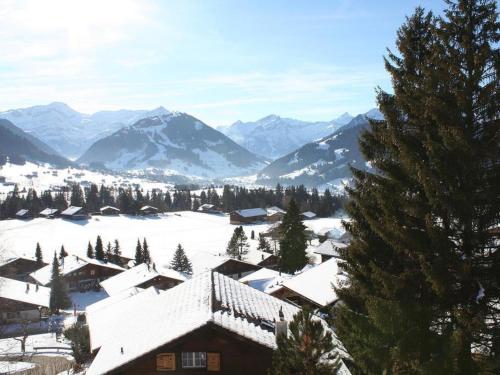 a snow covered village with mountains in the background at Apartment Sonnige Matte by Interhome in Gstaad