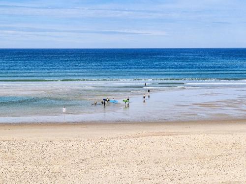 a group of people standing in the water on a beach at Holiday Home Sicard-3 by Interhome in Mimizan-Plage