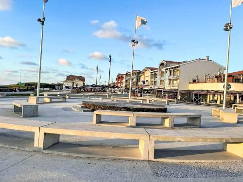 a group of benches in a plaza with buildings at Holiday Home Sicard-3 by Interhome in Mimizan-Plage