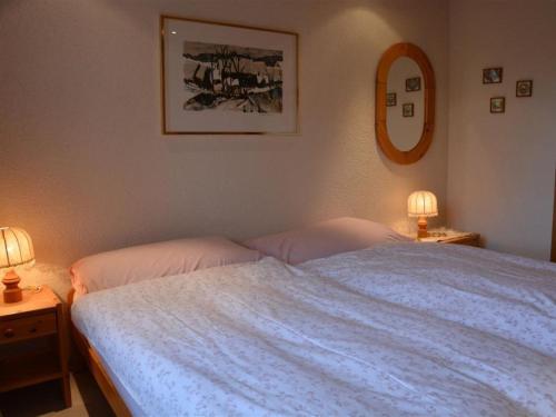 a bedroom with a bed with two lamps and a mirror at Apartment Hornflue - Wohlwender by Interhome in Gstaad