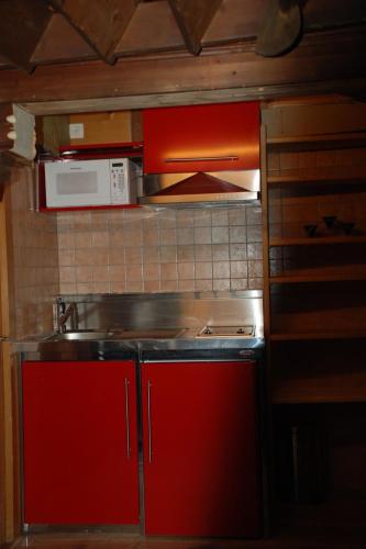 a kitchen with red cabinets and a sink and a microwave at Apartment Le Vieux Chalet by Interhome in Gstaad