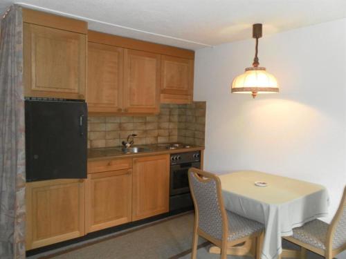 a kitchen with wooden cabinets and a table with chairs at Apartment Ammerten A17 by Interhome in Lenk