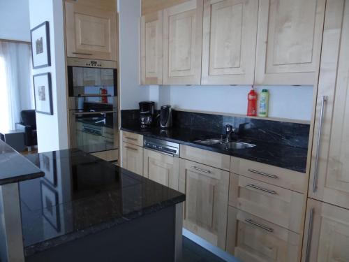 a kitchen with wooden cabinets and black counter tops at Apartment Dorfstrasse 7-42 by Interhome in Engelberg