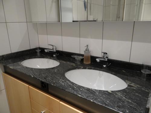 two sinks in a bathroom with two mirrors at Apartment Dorfstrasse 7-42 by Interhome in Engelberg