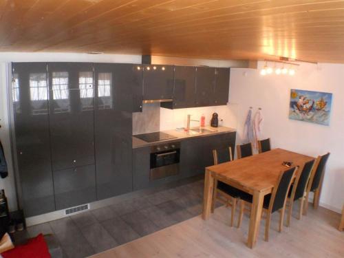 a kitchen with black cabinets and a wooden table at Apartment Kronenplatz 7 # 3 by Interhome in Lenk