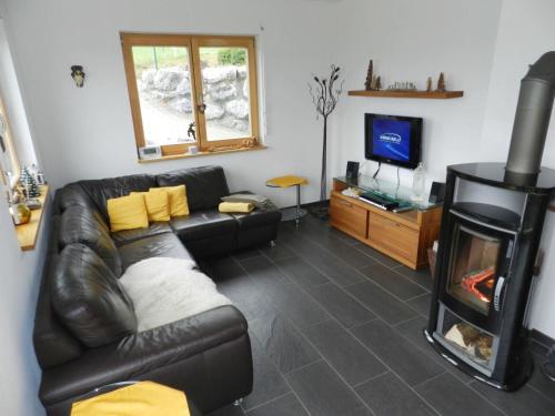 a living room with a black leather couch and a fireplace at Apartment Panorama- Chalet by Interhome in Blankenburg