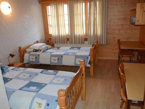 a bedroom with two beds and a table and chairs at Apartment Jacqueline 22 by Interhome in Gstaad