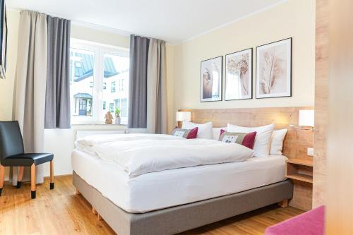 a bedroom with a large white bed and a chair at Simon´s Ferienwohnungen in Kurort Oberwiesenthal