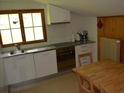 a kitchen with white cabinets and a table and a window at Apartment Chalet Heureka-Horbis by Interhome in Engelberg