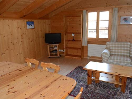 a living room with a table and a television at Apartment Jacqueline 24 by Interhome in Gstaad