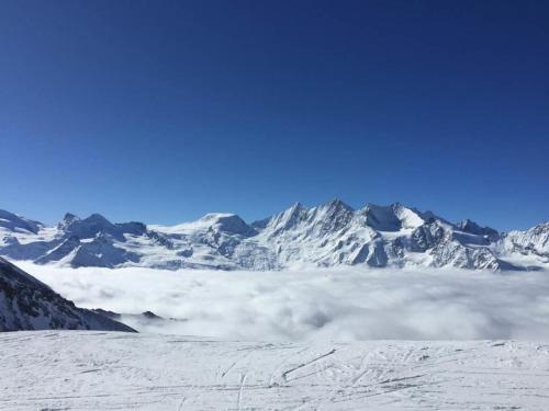 a snow covered mountain with clouds in front of it at Apartment Sunshine by Interhome in Saas-Grund