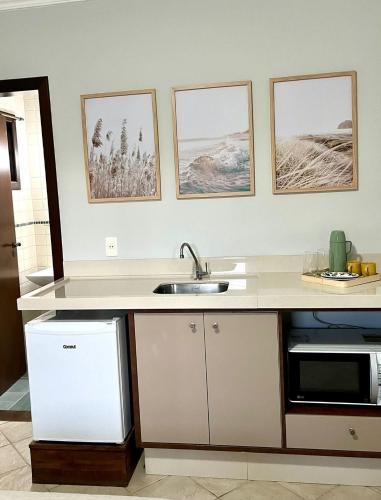 a kitchen with a sink and three pictures on the wall at Pousada Sunny Coast in Bombinhas