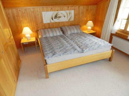 a bedroom with a bed with two lamps on two tables at Apartment Abendrot by Interhome in Gstaad